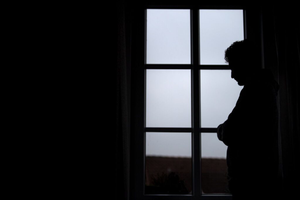 Ein Mann steht am Fenster seiner Wohnung