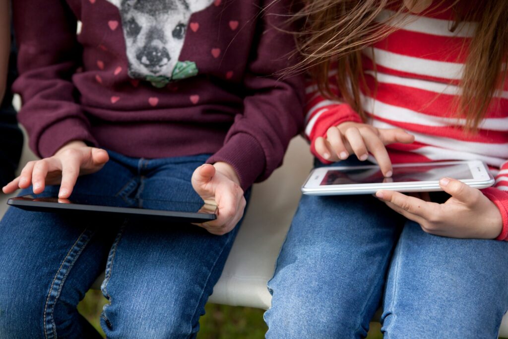 Zwei Kinder spielen etwas auf ihren Tablets