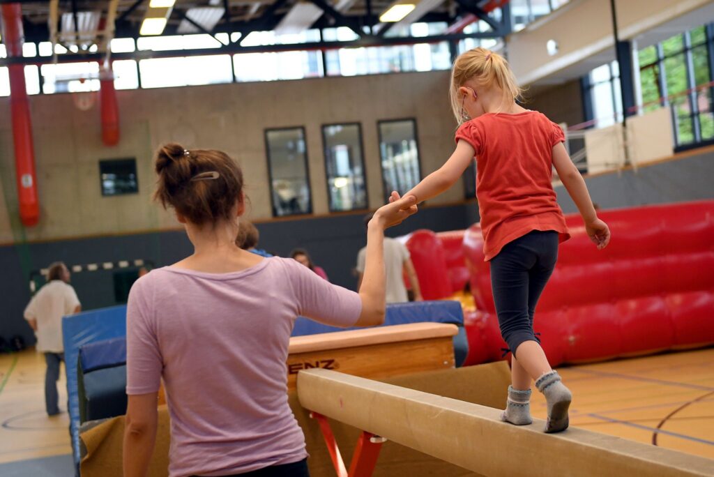 Eine Mutter hält ihre Tochter bei der Hand beim Kinder Turnen