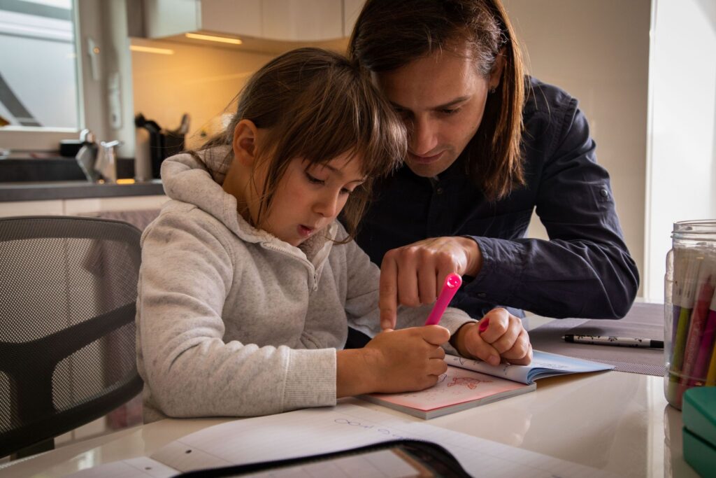 Ein Familienmitglied hilft der Tochter bei den Hausaufgaben