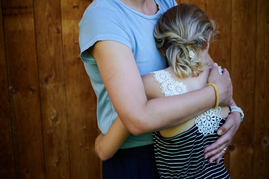 Ein Mädchen wird von seiner Mutter in den Arm genommen