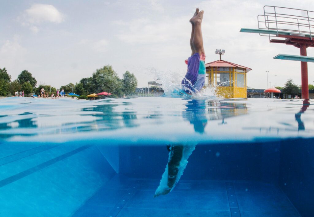 Schwimmer springt vom Sprungturm ins Wasser