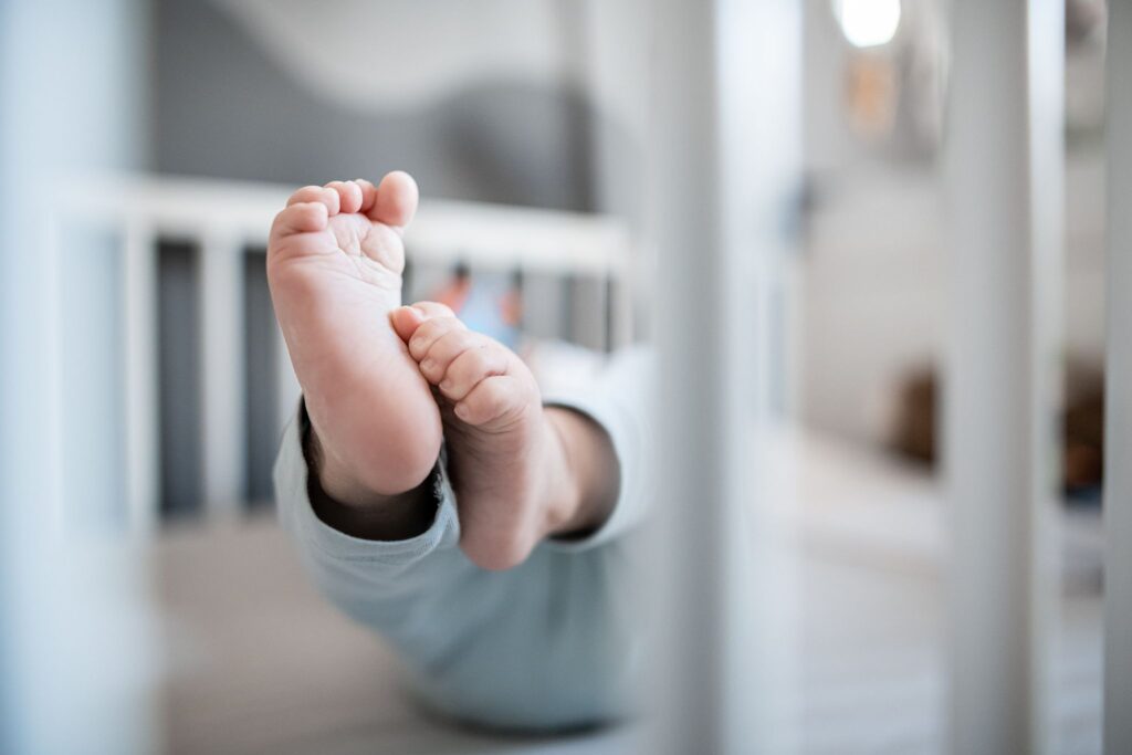 Die Füße eines Babys in einem Kinderbett