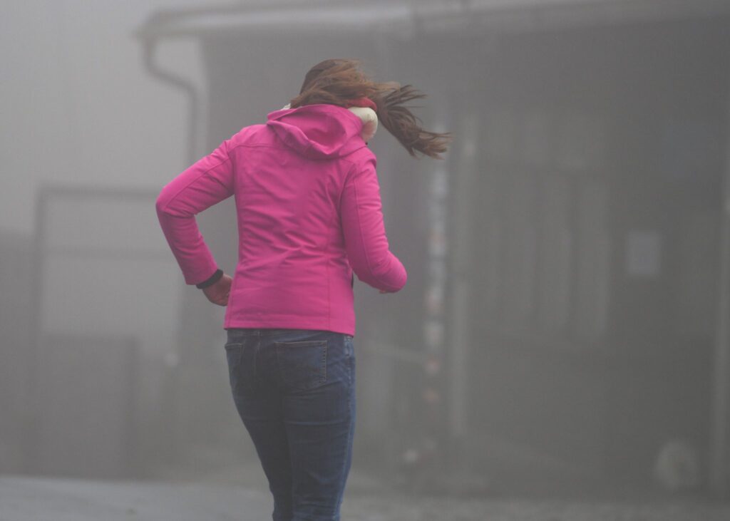 Frau kämpft auf dem Großen Feldberg im Taunus gegen Wind an